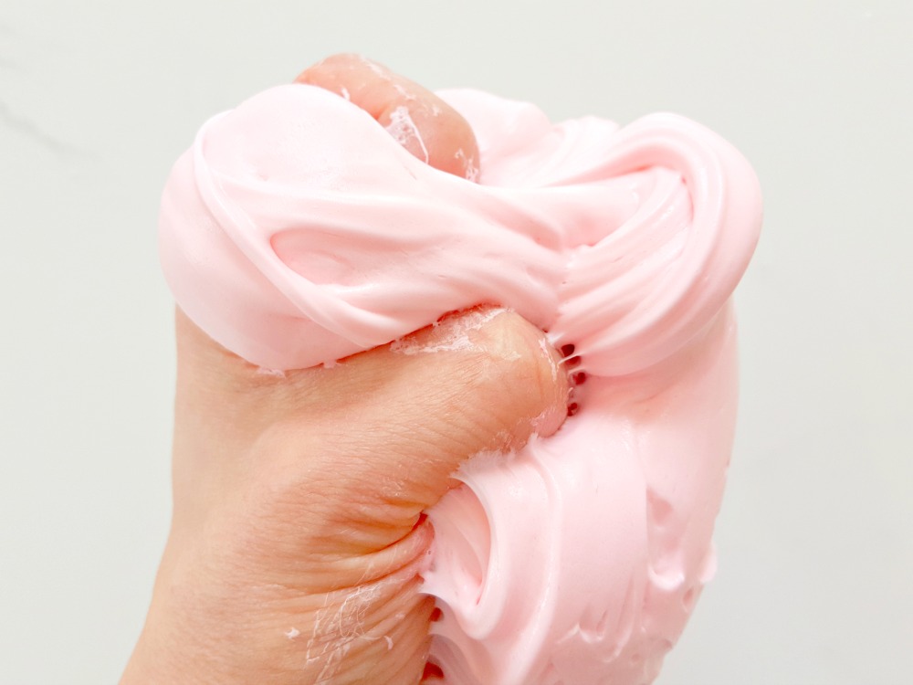 main qui tient une boule de Fluffy Slime rose sans borax